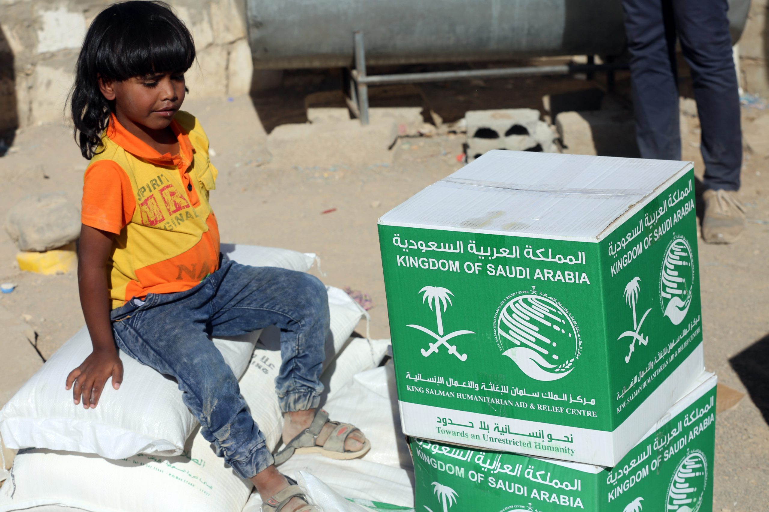 1261451 طفل يمنى يجلس بعد تلقى المساعدات السعودية1701871083 scaled